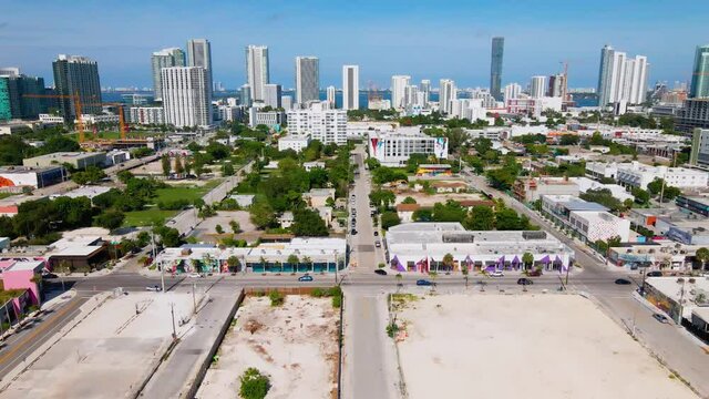 Aerial view over buildings and streets, in the Wynwood district, towards Skyscaper in Miami, Florida, sunny day, in USA  - dolly, drone shot