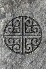 Ornamental print on the stone surface. Vintage ornament on the stone. Embossed drawing. Close-up. Stone texture. Pattern on the stone. Embossed pattern. Wallpaper. Tile