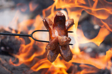 Sausage stabbed on an iron fork and toasted over an open fire