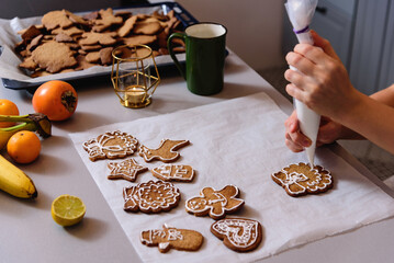 Decorating freshly baked cookies with icing. Christmas and New Year celebration traditions, festive sweets, family culinary. Traditional gingerbread. 