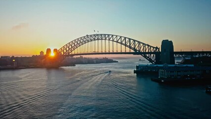 Picturesque sunrise over the Sydney Harbor Bridge with a solitary boat passing underneath. 