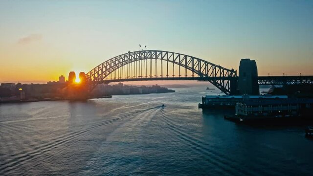 Picturesque sunrise over the Sydney Harbor Bridge with a solitary boat passing underneath. 