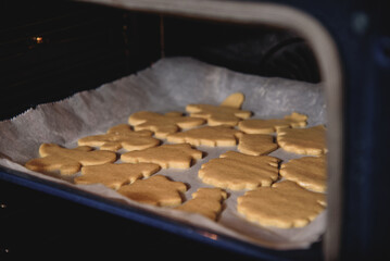 Steps of making Christmas cookies. Home kitchen with gray table. Ginger dough for gingerbread, gingerbread men, stars, Christmas trees, rolling pin, spices (cinnamon and anise)
