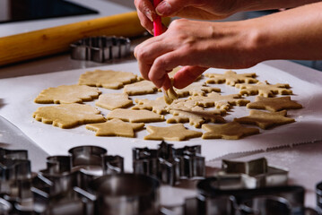 Steps of making Christmas cookies. Home kitchen with gray table. Ginger dough for gingerbread, gingerbread men, stars, Christmas trees, rolling pin, spices (cinnamon and anise)