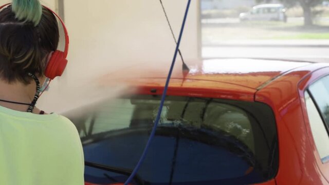 Woman cleaning red car with mask while listening to music, new normal