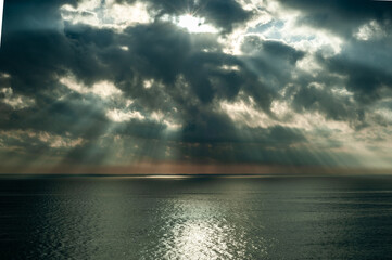 Obraz premium A great ray of sun breaks through the clouds and hits the sea.