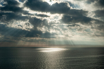 
A great ray of sun breaks through the clouds and hits the sea.