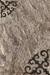 Ornamental print on the stone surface. Vintage ornament on the stone. Embossed drawing. Close-up. Stone texture. Pattern on the stone. Embossed pattern. Wallpaper. Tile