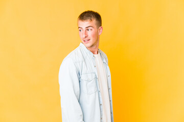 Young caucasian handsome man looks aside smiling, cheerful and pleasant.