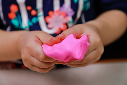 baby crumples pink plasticine with his hands