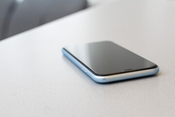 modern mobile phone with blank screen on black stone table background. Smartphone on old dark grey...