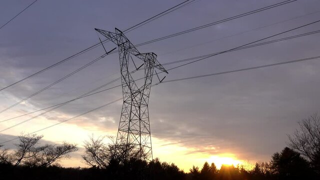 Electrical tower against a cloudy sky at sunset.