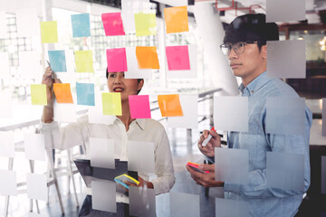 business teamwork in meeting and adhesive stick note on mirror board discussting with team in office room for collecting some idea brainstorming plan.