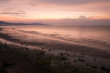 Fototapeta na wymiar Summer evening at Colwyn bay, North Wales. Warm summer sunset and a rocky beach
