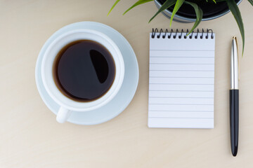 Obraz na płótnie Canvas Fountain pen, decorative plant, notepad and cup of coffee on wooden background. Business and copy space concept..