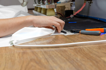 Men's hands work at the machine for welding PVC film and edging seam. Shop for the production of stretch ceilings.