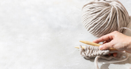 Female hands knitting with gray wool. Close up of knitting wooden knitting needles. Zero waste...