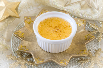 Creme brulee - traditional french vanilla cream dessert with caramelised sugar on top, served on a gold star-shaped plate with golden christmas decoration