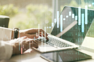 Abstract creative financial graph with hand typing on laptop on background, financial and trading concept. Multiexposure