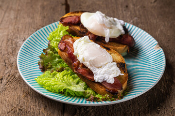 Hearty breakfast. Croutons with fried bacon, poached egg and lettuce.