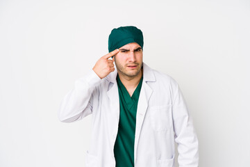 Young surgeon man isolated on white background showing a disappointment gesture with forefinger.