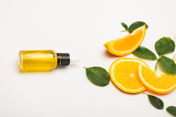 bottle of fresh homemade citrus essence near juicy orange slices and rose leaves on white, stock image