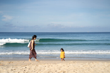 Mother and daughter walking at sea shore in Phuket Thailand.