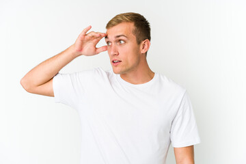 Young caucasian handsome man looking far away keeping hand on forehead.