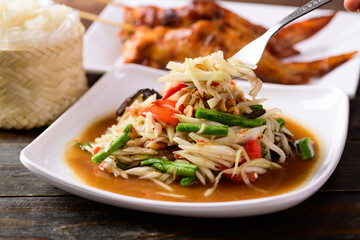 Thai food (Som Tum), Spicy green papaya salad eating with grilled chicken wing and sticky rice