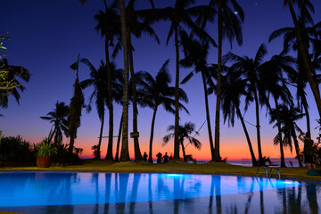 The pool is illuminated at night against the background of the sunset night sky. Diniwid beach...