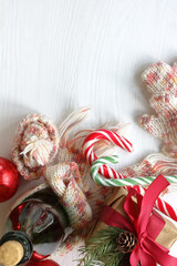 striped candy-sticks, knitted hat, scarf, mittens and a gift with a bottle of sparkling wine on the table top view. Christmas and New Year holidays