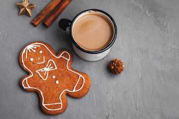 Decorative Christmas still life. Winter composition of gingerbread man in the shape of a cookie on a gray textured table background. Cup of coffee, breakfast. Flat lay, top view. Copy space