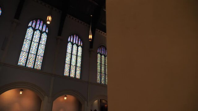 Stained Glass Windows and Ambience in Protestant Christian Church,  Slow Motion Revealing Behind Column