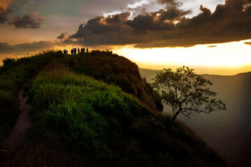 tourist on mountain top against beautiful sunset sky