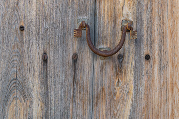 Close-up of an antique iron knob on an antique wooden door
