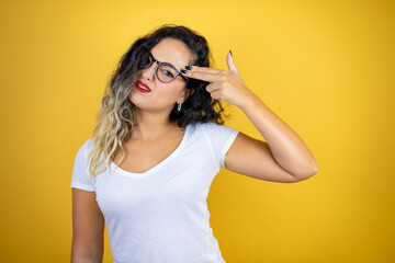 Young beautiful woman wearing casual white t-shirt over isolated yellow background Shooting and killing oneself pointing hand and fingers to head like gun, suicide gesture.