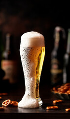 Beer in a glass glass, the foam flows down the glass. Beer publ. Beer snack - salty pretzels