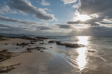 Partly cloudy morning by the sea. Rocks at sea shore under a sunny and partly cloudy morning.