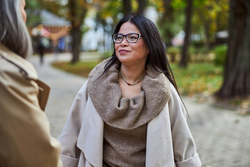 Beautiful joyful woman talking with friend on the street