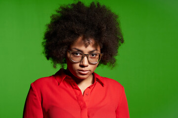 Fototapeta na wymiar Discontent serious young African-American girl in glasses and red shirt
