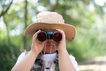 An adventure boy is using a binocular.