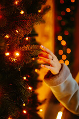 Woman's hand with christmas lights on the tree. Festive Christmas fair, winter holidays concept.