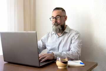 Bearded man working on laptop in home office
