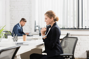  businesswoman looking at laptop, while sitting at workplace on blurred background