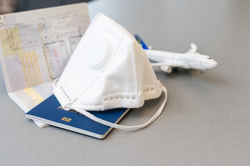 Plane toy, passport, face mask on gray background. Flight cancellation due to the impact of coronavirus COVID-19 concept.