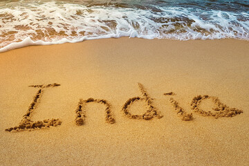 India title on the sand beach of the coast Indian ocean. Wave.