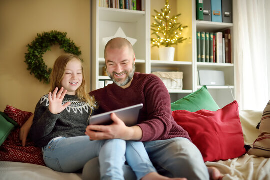 Father And His Daughter Having Online Video Call On Christmas Time. Chatting With Distant Family During Pandemic. Staying Safe During Winter Holidays.