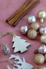 Various Christmas decorations and cinnamon sticks on pink background. Selective focus.