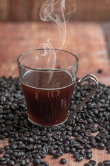 A cup of coffee with coffee beans over a wooden table.