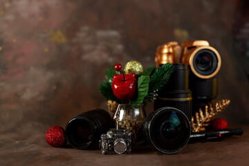 Obraz na płótnie Canvas christmas and new year background for photographer. christmas set gold camera and lenses and christmas tree toys on dark background horizontal orientation